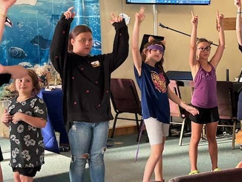 Kids and leader worshipping together at VBS
